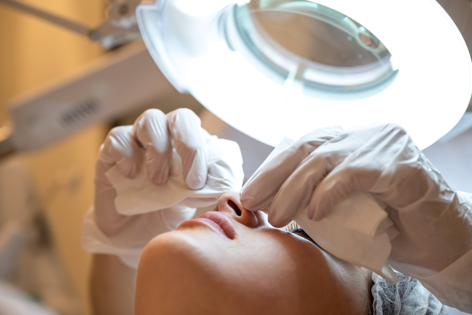 Closeup of woman's head at a beautician appointment. Manual facial cleansing. Cleansing facial skin, beautician squeezed blackheads. Low angle view.